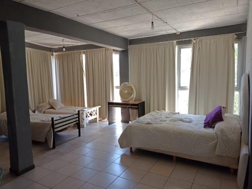 a bedroom with two beds and a chair and windows at Complejo Navi in Mina Clavero