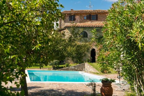 a swimming pool in front of a house with trees at Podere L'Aquila in Gaiole in Chianti