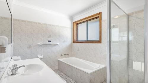 een witte badkamer met een wastafel en een douche bij The Penguins Head in Culburra Beach