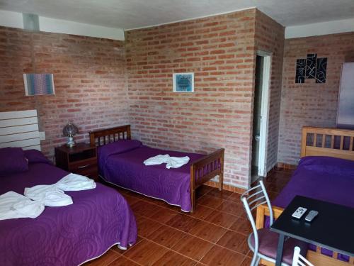Habitación con 2 camas y pared de ladrillo en Complejo Navi, en Mina Clavero