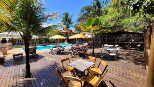un patio extérieur avec des tables et des chaises ainsi qu'une piscine dans l'établissement Pousada Beach Bahia, à Porto Seguro