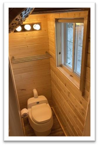 a small bathroom with a toilet and a window at Our Cabin Bed & Breakfast in Yellowknife