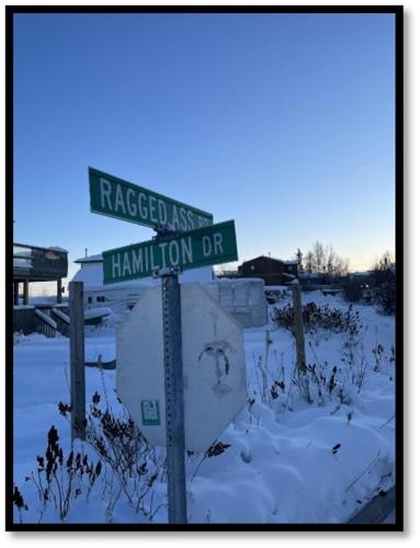um sinal de rua em cima de um sinal de stop na neve em Our Cabin Bed & Breakfast em Yellowknife
