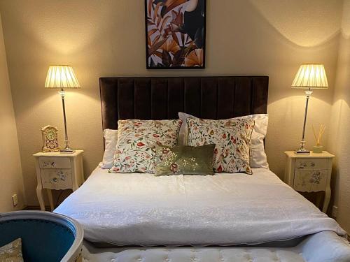 a bedroom with a bed with pillows and two lamps at Bird In Bush Elsdon in Elsdon