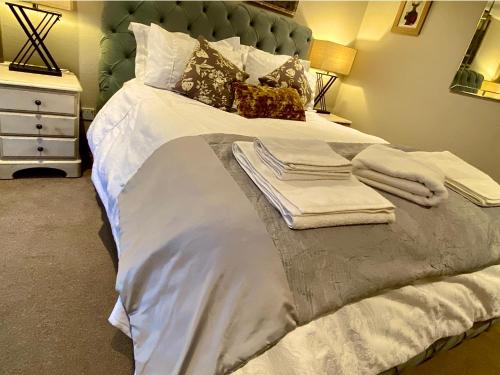 a large bed with white sheets and towels on it at Bird In Bush Elsdon in Elsdon