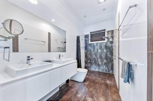 a white bathroom with two sinks and a shower at Seascape Paradise in Airlie Beach