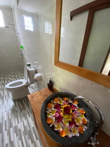 La salle de bains est pourvue d'un lavabo avec un bol de fleurs. dans l'établissement Pondok Serayu, à Ubud