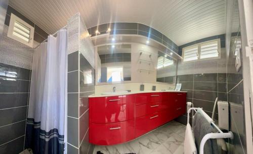 La salle de bains est pourvue d'un lavabo et d'une armoire rouges. dans l'établissement Villa La roche, à Le Moule