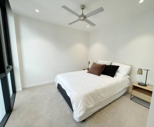 - une chambre avec un lit blanc et un ventilateur de plafond dans l'établissement Chermside deluxe 3 bedroom brand new apartment, à Brisbane