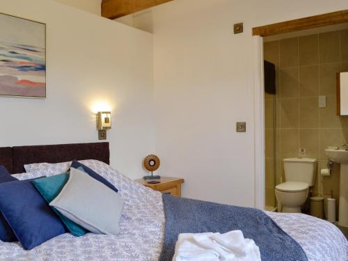 a bedroom with a bed and a bathroom with a toilet at Court Park Barn in Tidenham