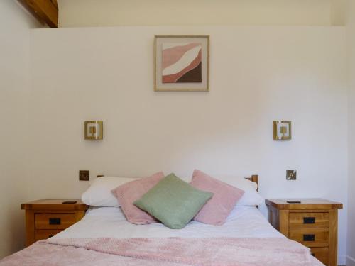 a bed with pink and green pillows on it at Court Park Barn in Tidenham