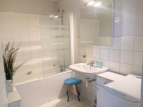 La salle de bains blanche est pourvue d'un lavabo, d'une baignoire et d'une douche. dans l'établissement Appartement lumineux avec ascenseur, balcon et wifi gratuit à Granville - FR-1-361-123, à Granville