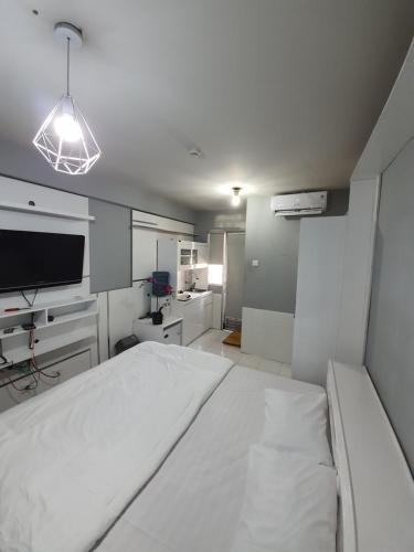 um quarto branco com uma cama grande e uma televisão em Bassura City Apartment by Sang Living em Jakarta