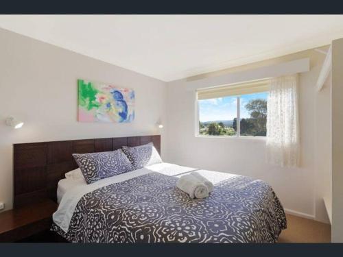 a bedroom with a bed with a hat on it at Top of the Lake Holiday Units in Merimbula