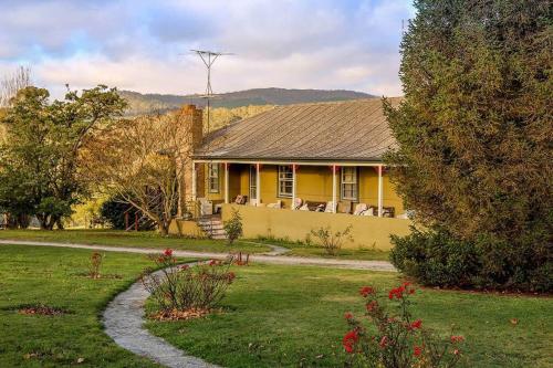 a yellow house in a yard with a driveway at Duckmaloi Park Lodge in Oberon