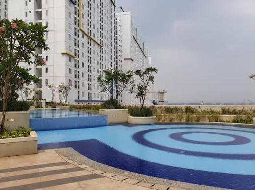uma grande piscina azul em frente a um edifício em Bassura City Apartment by Sang Living em Jakarta