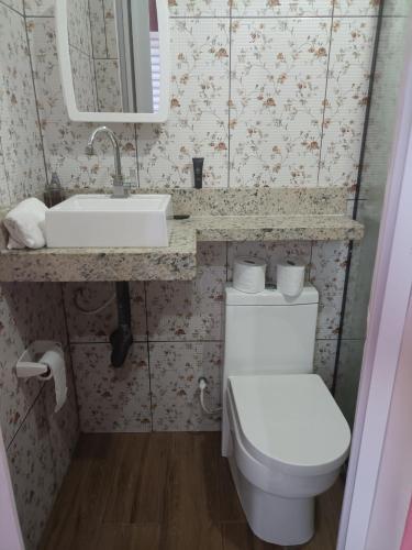 a bathroom with a toilet and a sink and a mirror at Mini casa pé na areia in Ilhéus