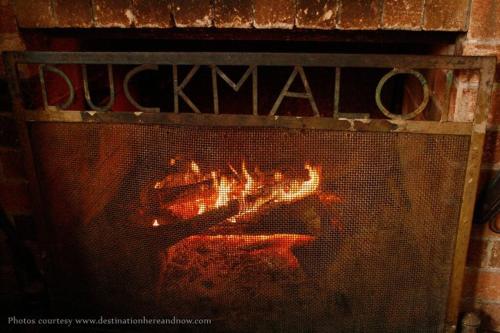 a brick fireplace with a fire in it at Duckmaloi Park Lodge in Oberon