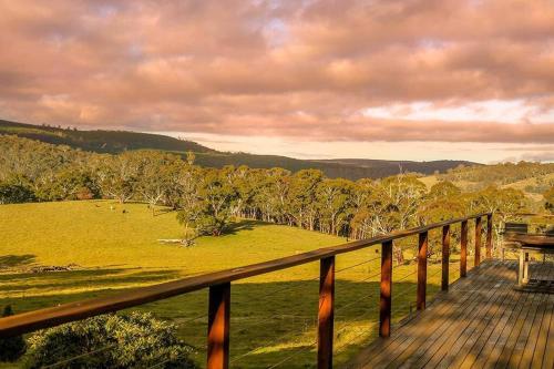 a wooden deck with a view of a field and trees at Duckmaloi Park Lodge in Oberon