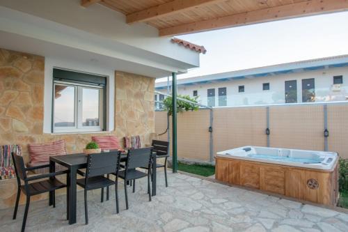 a patio with a table and chairs and a hot tub at Sea View Holiday Homes - Omega Estate Resorts in Kipseli