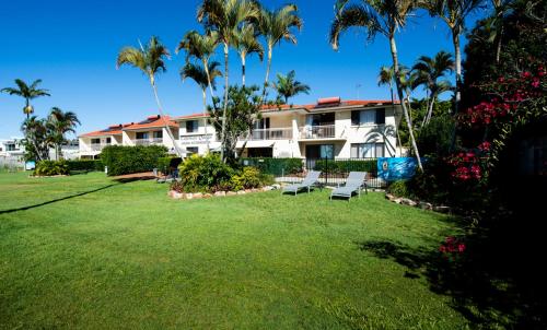 a house with palm trees and a large yard at Cayman Quays in Noosaville