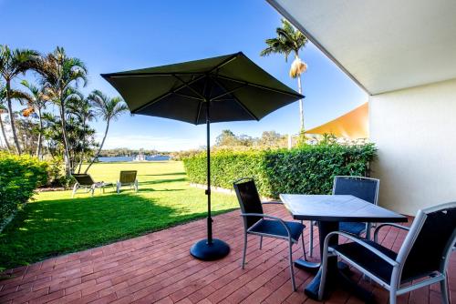 a patio with an umbrella and a table and chairs at Cayman Quays in Noosaville