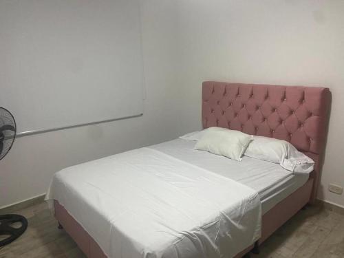 a bed with a pink headboard in a room at Apartamento en hacienda peñalisa mango, Ricaurte in Ricaurte