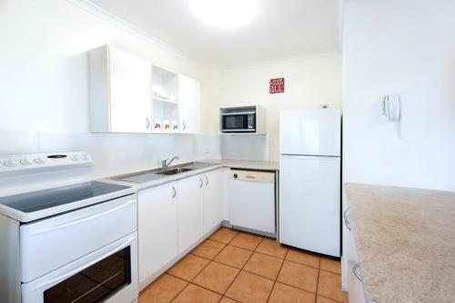 a white kitchen with a sink and a refrigerator at Cayman Quays in Noosaville