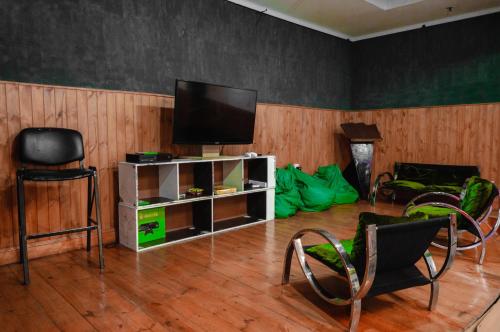 sala de estar con TV de pantalla plana y sillas en Clover Hostel en Mendoza