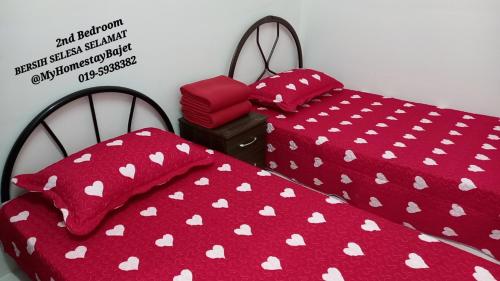 2 camas con edredón rojo y almohadas rojas en Cikgu Huda Homestay Bajet en Seri Manjung