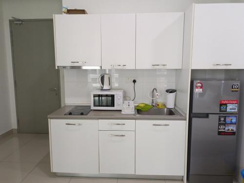 a kitchen with white cabinets and a stainless steel refrigerator at Peace home cybersqure 2 in Cyberjaya