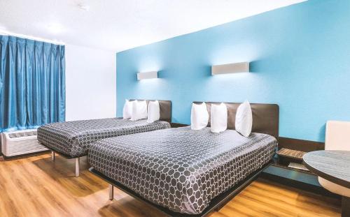 two beds in a room with blue walls at Americas Best Value Inn Beeville in Beeville