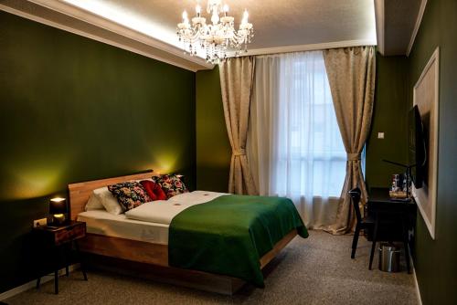 a green bedroom with a bed and a chandelier at Hotel-Residenz-Luxury-Apartments in Metzingen