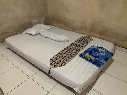 1 cama con sábanas blancas y almohadas en una habitación en Aren Homestay, en Giripurno