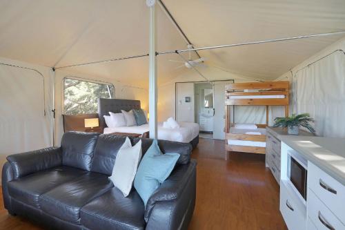 a living room with a couch and a bed in a tent at Reflections Bonny Hills - Holiday Park in Lake Cathie