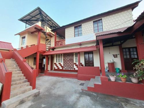 a building with red trim and stairs in front of it at Odyssey's Pateng Homestay, Cherrapunji in Cherrapunji