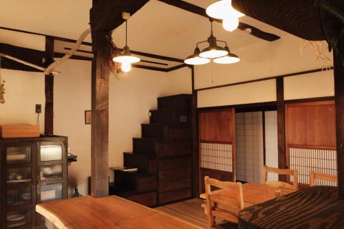 a living room with a table and a staircase at Guesthouse SHIGI in Nakatsugawa