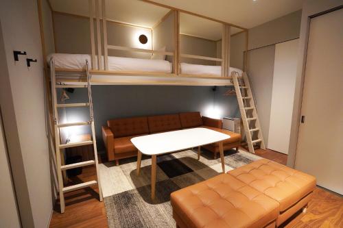 a room with bunk beds and a couch and a table at Riverside Hotel Sapporo in Sapporo