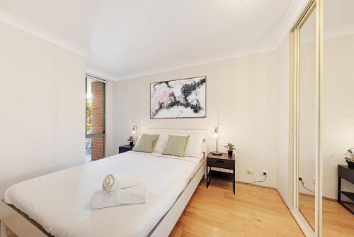 ein weißes Schlafzimmer mit einem großen Bett und einem Spiegel in der Unterkunft Spacious & Cosy 2 Bedroom Apartment in Darling Harbour in Sydney