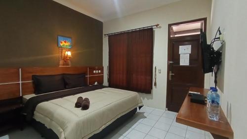 Un dormitorio con una cama con un par de zapatos. en Yokima Beach Hotel en Pangandaran