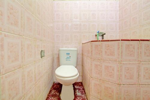 baño con aseo en una habitación con paredes rosas en SPOT ON 92188 Ndalem Eyang Guesthouse Syariah, en Demak