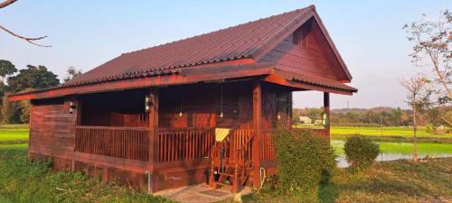 a small building with a brown roof in a field at DGD Chiangmai in Mae Rim