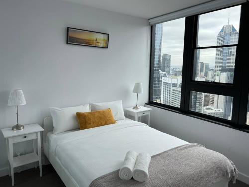 a bedroom with a white bed and a large window at Pars apartments - Melbourne Quarter- unique View of city and Yarra in Melbourne