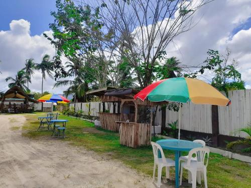 a table and chairs with a colorful umbrella at TheSoftbed Homestay in San Vicente