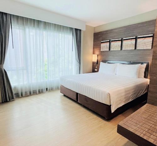 Citrus Sukhumvit 11 by Compass Hospitality في بانكوك: غرفة نوم بسرير كبير ونافذة كبيرة