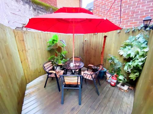 un patio con mesa, sillas y sombrilla roja en Aroha Guesthouse Seoul Station en Seúl