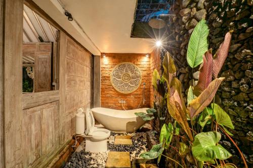 a bathroom with a bath tub and a toilet and plants at Pratiwi Ubud Villa in Ubud