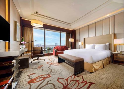 a bedroom with a large bed and a living room at Sanding New Century Grand Hotel Yiwu in Yiwu