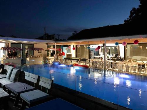 a swimming pool with chairs and a restaurant at night at אחוזה 14 in Ẕafriyya