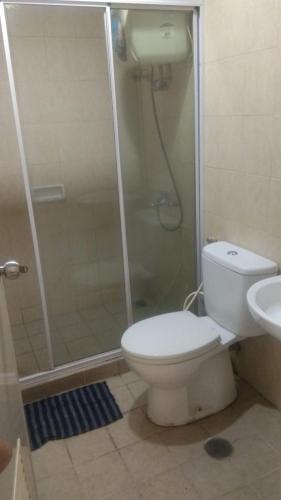 uma casa de banho com um chuveiro, um WC e um lavatório. em Disewakan Apartemen Aston Marina Ancol em Jacarta